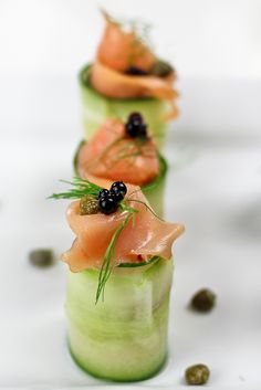 three small cups filled with food on top of a white table covered in black olives