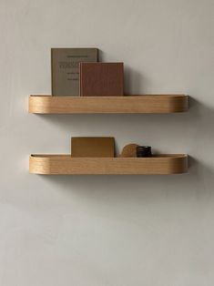 two wooden shelves with books on them against a wall