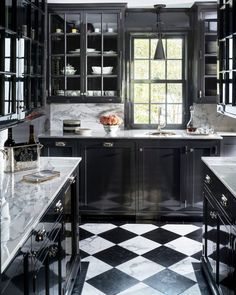 a kitchen with black cabinets and marble counter tops