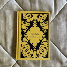 a yellow book sitting on top of a bed next to a white sheet with black writing