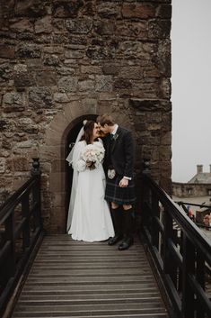 a bride and groom kissing on a bridge