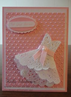 a pink card with white doily on it, and a bow at the top