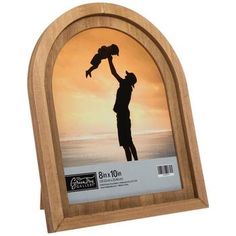 a wooden frame with a silhouette of a man holding a baby in his arms on the beach