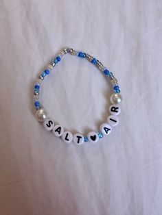 a beaded bracelet with the word santa written in white and blue beads on it