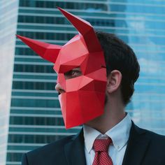 a man wearing a devil mask in front of a skyscraper