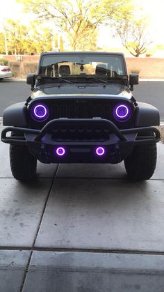 the front end of a black jeep with purple lights on it's grilles