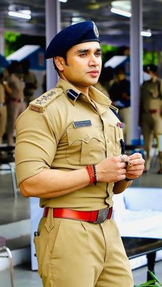 a man in uniform is posing for the camera with his hand on his hip and looking at his cell phone