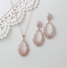 This rose gold necklace and earring set is perfect for special occasions. Featuring a sophisticated hoop style design, the set is adorned with sparkling cubic zirconia stones, making it a stunning choice for bridal jewelry. Elevate any outfit with this elegant and timeless set. Earrings measure 2.25" x 1" Necklace length 16 inches extends to 18 inches Pendant measures 2" x 1.125" Matching bracelets: https://www.etsy.com/listing/489107525/bridal-tennis-bracelet-rose-gold?click_key=59aaaf3f952d0eba017a1664c344288c5ffb87f9%3A489107525&click_sum=226dd81d&ref=shop_home_active_1&pro=1&frs=1&sts=1 https://www.etsy.com/listing/549791929/rose-gold-bridal-bracelet-bridal-jewelry?click_key=37d173e3ab72e0ebfa1174d7e8256fc27a90cef2%3A549791929&click_sum=1a44da13&ref=shop_home_active_4&pro=1&frs=1&sts=1 Bracelet Rose Gold, Rose Gold Jewelry Set, Pink Jewelry Set, Rose Gold Bridal Earrings, Rose Gold Hoop Earrings, Rose Gold Bridal, Rose Gold Bracelet, Pink Jewelry, Bridal Bracelet