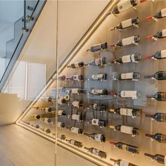 a glass display case filled with lots of wine bottles next to a stair case in a building