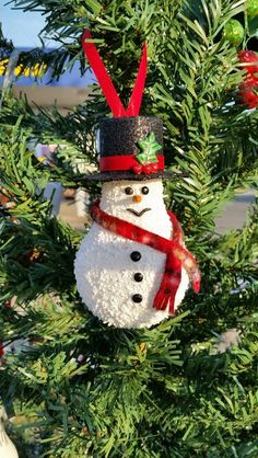 a snowman ornament hanging from a christmas tree