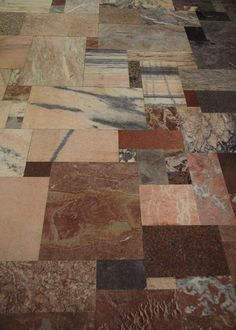 the floor is made up of many different colors and shapes, including red, brown, blue, black, gray and white marble