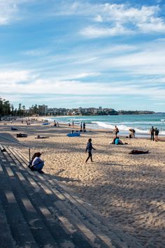 many people are on the beach and one person is laying in the sand with his surfboard