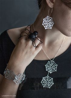 a woman wearing spider web necklaces and earrings