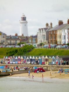 the beach is crowded with people and colorful houses in the backgroung area