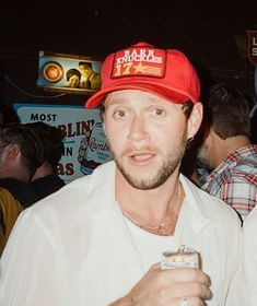 a man wearing a red hat and holding a drink in his hand at a party