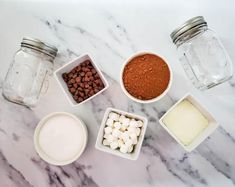 the ingredients are in small bowls on the marble counter top, including marshmallows and chocolate chips