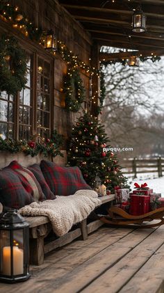 a wooden porch covered in christmas decorations and lit up trees with presents on the bench