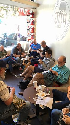 a group of people sitting on couches in a living room eating and drinking coffee