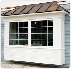 a white window sitting on the side of a blue building with a brown roof and shingled windows