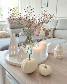 a table topped with candles and white pumpkins on top of a wooden table next to a couch