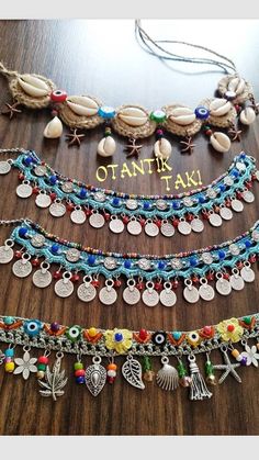 several different necklaces with charms on them sitting on a table next to each other