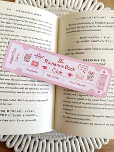 an open book sitting on top of a white doily next to a pink sticker