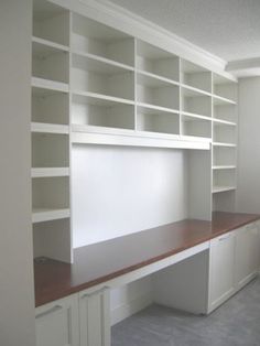 an empty room with white bookcases and wooden shelves