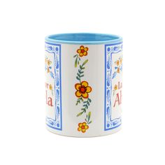 a blue and white cup with flowers painted on the side, sitting in front of a white background