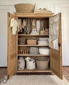 an open closet with baskets and clothes on it's shelves, next to a rug