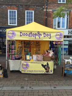 a dog is standing in front of a booth selling books and other items on the street