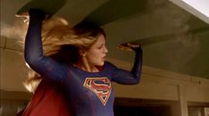 a woman in a superman costume is holding her hair back and looking at the camera