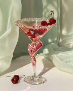 a martini glass with cherries on the rim