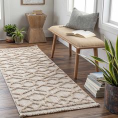 a living room with wooden floors and white walls, along with a large rug on the floor