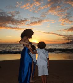 two children on the beach at sunset, one holding onto another child's arm