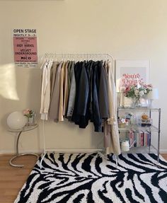 a room with a zebra print rug and clothes hanging on a rack in the corner