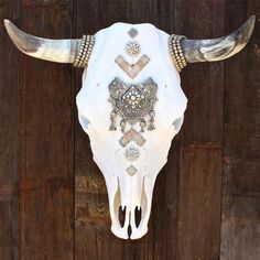 a cow skull with intricate designs on it's face hanging from a wooden wall