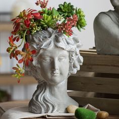 a statue with flowers in its head sitting on a table