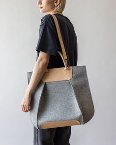 a woman carrying a gray and tan tote bag on her back, side view