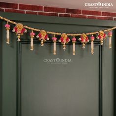 a string of beads hanging from the side of a green door with pink flowers on it