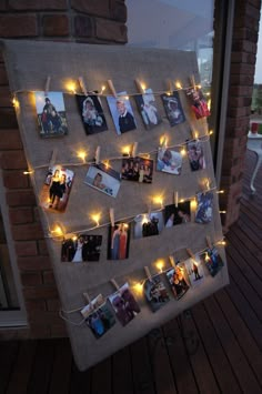 a bulletin board with pictures hanging on it and string lights strung from the pegs