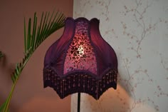 a purple lamp shade sitting on top of a wooden table next to a palm tree