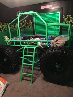 a green monster truck bed with flames on it's sides and two large tires