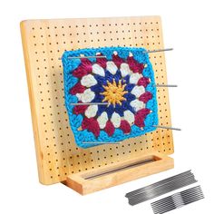 a crocheted square with pins in the middle on a peg board next to it