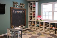 a child's playroom with toys and bookshelves on the wall, including a chalkboard