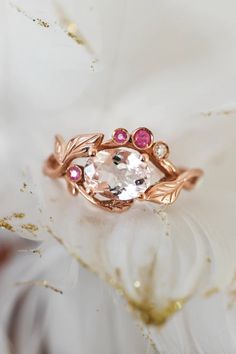 a close up view of an engagement ring with pink sapphires and leaves on it