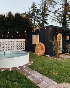 an outdoor hot tub in the middle of a yard with string lights strung around it