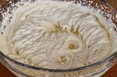 a glass bowl filled with batter on top of a wooden table