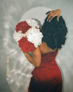 a woman in a red dress holding a bouquet of flowers with her hands behind her back