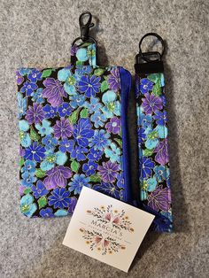 two blue and purple flowers are on the ground next to a card holder with a note