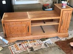 a wooden entertainment center sitting on top of a pile of newspaper next to a door